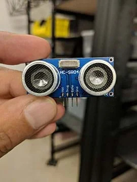 A Sunfounder ultrasonic device, containing two input sensors on a blue board with four output pins.