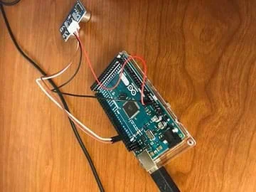 The image shows a breadboard with a USB cord connected to it.  Connected to the digital pins of the breadboard are the echo and trigger wires that connect to an ultrasound distance sensor.  The power and ground wires are connected on the opposite side near the analog pins.