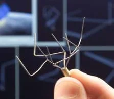 Photo shows a thumb and forefinger holding a small antenna that looks like miniature antlers made from bent silver wire.