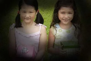 A photograph of two young girls looking at a camera. The edges of the image have a black vignette—a loss in clarity towards the corners and sides of an image—which portrays what is seen when damage to the optic nerve has occurred due to the effects of glaucoma.