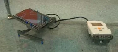 A photograph shows a turntable made of LEGO pieces holding a smartphone and connected to a LEGO intelligent brick.