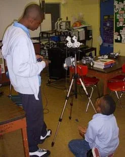 A photograph shows two boys in a classroom near a tripod with a device four-wheeled LEGO device mounted on it.
Source/Rights: 2012 Jeffrey Laut, AMPS, NYU-Poly