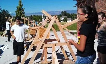 A photograph shows students preparing to launch a trebuchet designed and built during a summer high school course.