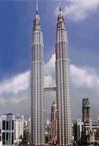 A photograph shows two twin skyscrapers with a horizontal bridge connecting them midway.