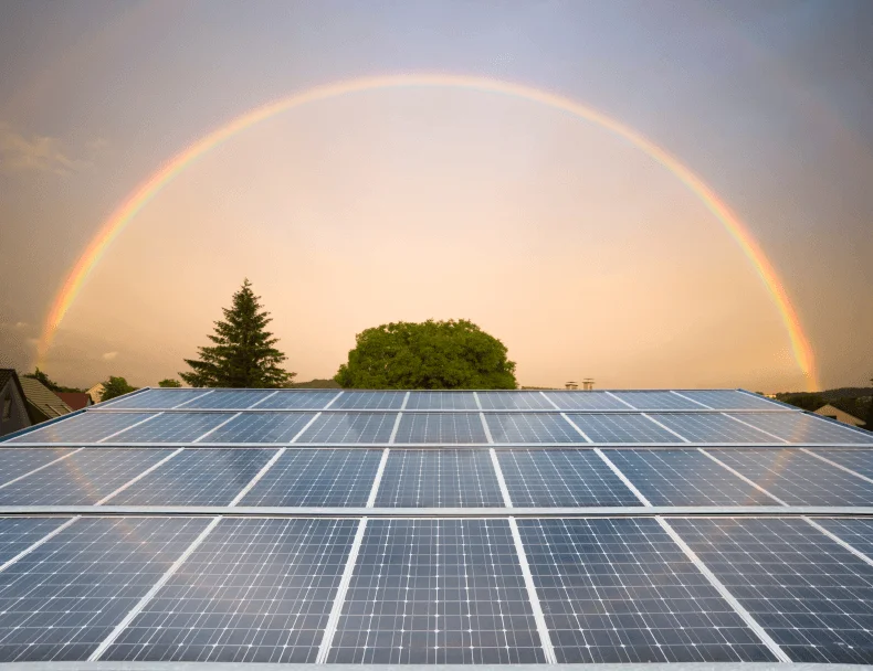 Rooftop solar panels under a rainbow
