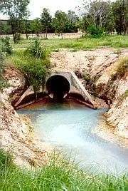Photo shows a big, buried concrete pipe opening out into a gully.