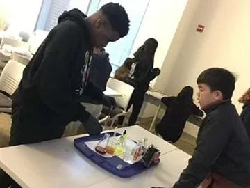Two students at a lab station use a microscope.
