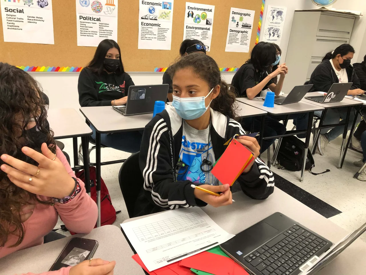 A photo of a student holding up a red index card to show another student.