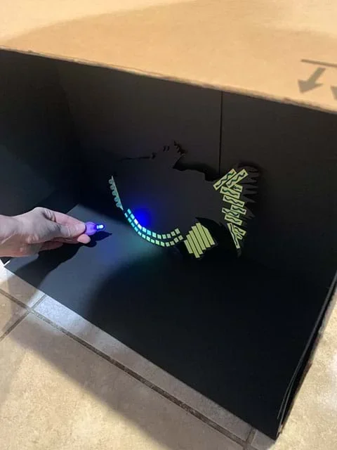 An aquatic organism cut-out on black cardstock expressing bioluminescence with fluorescent materials such as glow-in-the-dark tape, UV beads, and glow paint.