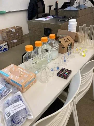 A table containing laboratory supplies needed to create hydrogels sits in a classroom.