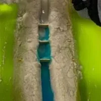 An image showing the movement of pollutants, symbolized by food coloring, as they flow downstream within an engineered bayou system. The bayou is strategically designed to contain and prevent the spread of pollutants along its banks.