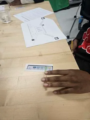 A photo showing a student using a glucose testing strip to test liquids and compare the resulting color.