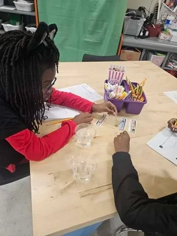 A photo showing a student holding a glucose testing strip next to a color chart.
