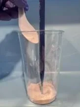 A photo showing the baking soda at the bottom of the cup and colored vinegar in the dropper setup prior to layering the clay, gravel, and sand.