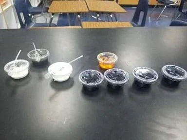 Eight solo cups filled with dye solutions and white solutions of nanoparticle samples.