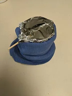 A photograph shows a beaker and skewer setup wrapped in a towel and covered with aluminum foil.