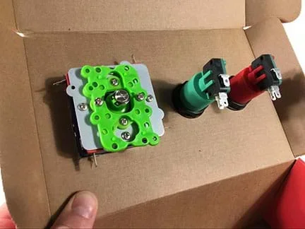 A photograph from inside the shoebox shows the underside of the joystick and buttons that are mounted on top of the box.