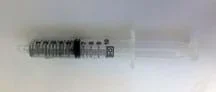 Photo shows a coiled metal spring inside a clear, plastic 20 ml syringe with another plastic piece fitted inside the syringe cylinder to close it off.