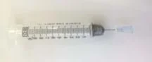Photo shows a clear, plastic 20 ml syringe, whose opening is covered in duct tape. A pin is stuck inside the duct tape-covered orifice to make a tiny hole.