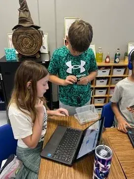 A photo showing two students working together to code their micro:bits to show how the eye sees an image and then the retina signals the inverse to the brain.