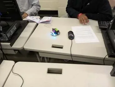 A photo showing students sitting at a desk with the code for LED display on the ELECFREAKS Cutebot.