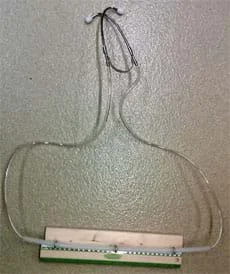 Photo shows a device made from the two metal ear pieces of a stethoscope each attached to clear plastic tubing that runs through metal eyelet screws attached to a piece of wood.