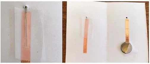 Two photographs. The left shows a closeup of the lefthand side of the card element. A piece of tape facing up has been placed on top of the already taped short wire and the long wire has been pushed down. The right photograph shows the entire card from farther away.