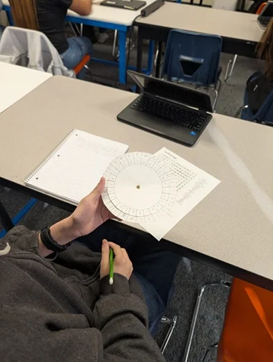 A photo showing a student holding a decoder wheel at a worktable.