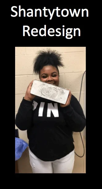 A photograph shows a female student holding a rectangular concrete block in a classroom; photo is surrounded by a black border with the title “Shantytown Redesign.”