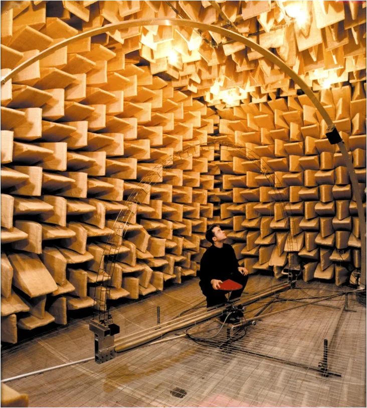 An acoustical engineer measures a sound instrument inside an anechoic chamber.