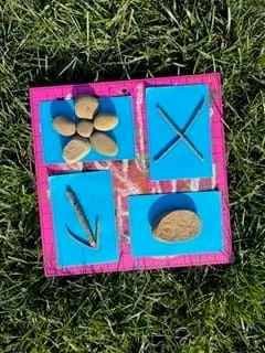 A photo showing objects found from nature (rocks, sticks, flowers) placed on construction paper, then exposed to sunlight to begin the cyanotype printing process.