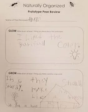 A photograph of a peer review conducted by a student. The student writes that she liked the beautiful color and that it could be improved if it were made like a house.