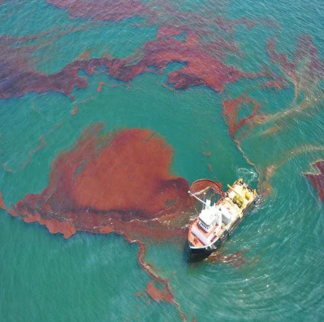 A 2010 photograph from the Deepwater Horizon oil spill in the Gulf of Mexico. The photo shows a boat sailing through an oil slick.