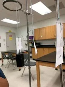 Photo of three hanging paper strips, one of which has a large mass hanging from it.