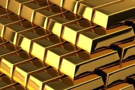 Photo shows a stack of rectangular pure gold bars that are highly reflective, and a bright yellow-gold color.