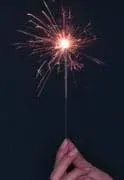 Photo shows a hand holding a burning sparkler.