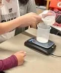 A photo showing students measuring glue on the weight scale.