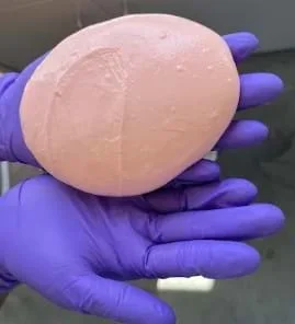 A photo showing a gloved individual holding Controlled Slime (3.33% borax solution).