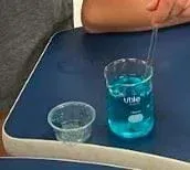 A picture of an unset blue gel in a beaker.