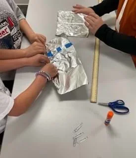 A photo showing three students at a table working on their aluminum rope.
