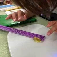 A photo showing a student measuring the length of a gummy with a centimeter ruler.