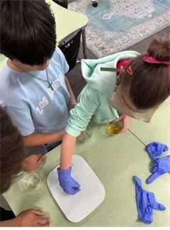 A photo showing three students weighing a gummy prototype on a gram scale.