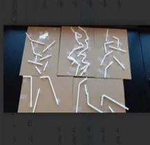 A photo showing five cardboard sheets, each featuring several white plastic drinking straws, some straight and others bent at the flexible neck, taped down with clear adhesive tape.