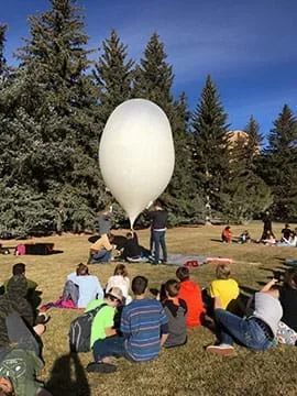 The balloon is filled with helium as students observe. Once the balloon is filled it is released and travels upwards into the sky, carrying the payload and any additional materials needed.