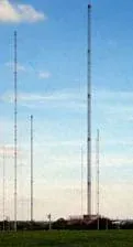 A photograph shows about five metal truss radio towers, secured by numerous guy wires anchored at angles in the surrounding ground.