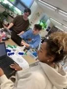 A photo showing three students referencing the codon wheel as they organize the amino acids they will use to construct a model of a polypeptide.